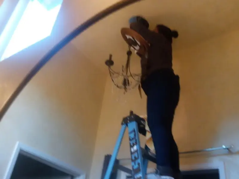 Electrician installing a chandelier in a Muskogee residence